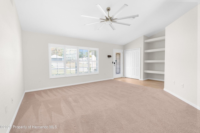 carpeted empty room featuring lofted ceiling and built in features