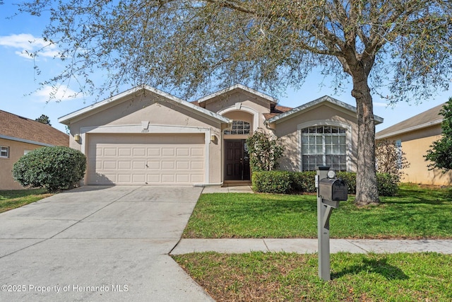 ranch-style home featuring a garage, concrete driveway, a front lawn, and stucco siding