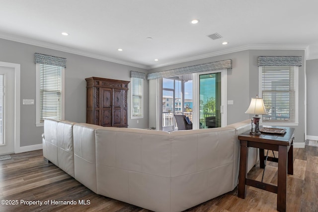 living room featuring baseboards, crown molding, visible vents, and wood finished floors