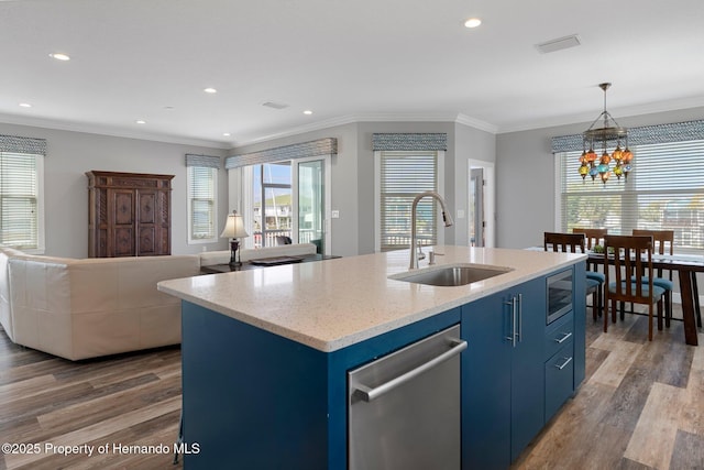 kitchen featuring blue cabinetry, a kitchen island with sink, open floor plan, and a sink