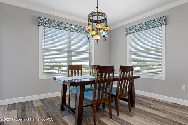 dining area with baseboards, dark wood-style flooring, a notable chandelier, and ornamental molding