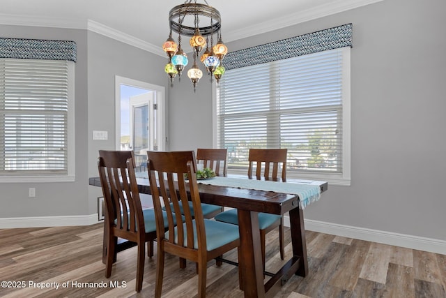 dining room featuring baseboards, a chandelier, wood finished floors, and ornamental molding