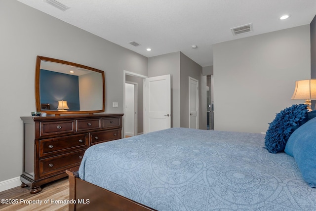 bedroom with light wood finished floors, baseboards, visible vents, and recessed lighting