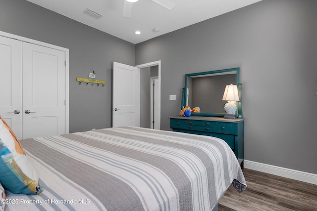 bedroom featuring dark wood-style flooring, a ceiling fan, visible vents, baseboards, and a closet