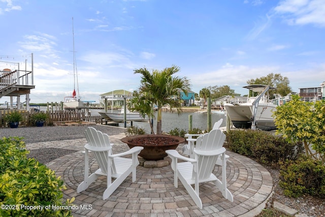 view of patio with a water view, an outdoor fire pit, boat lift, and a boat dock