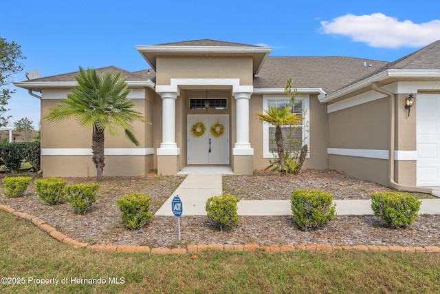 property entrance featuring a shingled roof, an attached garage, and stucco siding