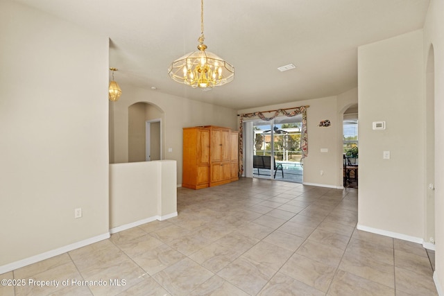 empty room featuring arched walkways, light tile patterned floors, baseboards, and a notable chandelier