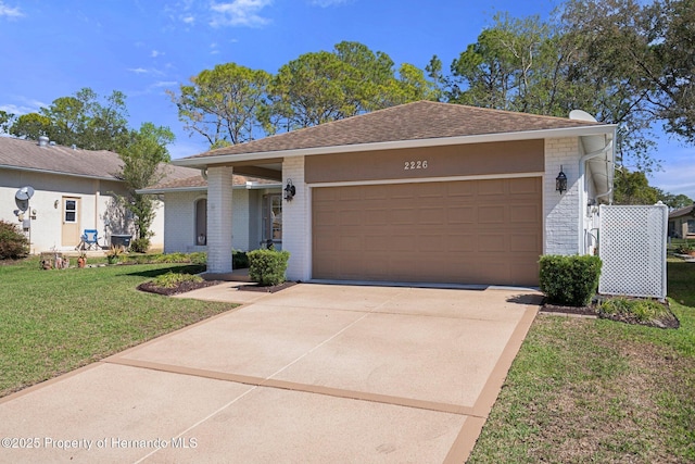 ranch-style home with concrete driveway, roof with shingles, an attached garage, a front lawn, and brick siding