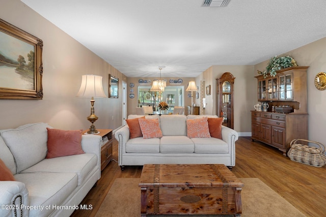 living room with baseboards, visible vents, and wood finished floors