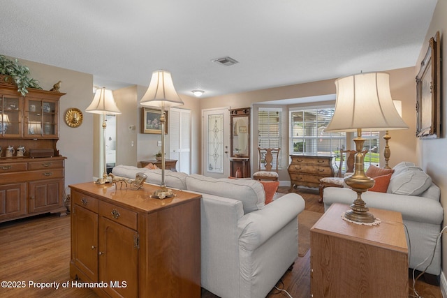 living area with visible vents and wood finished floors