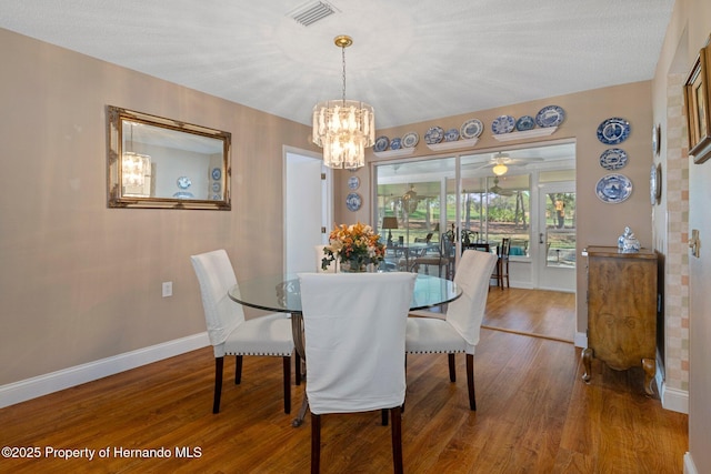 dining area with a notable chandelier, baseboards, visible vents, and wood finished floors