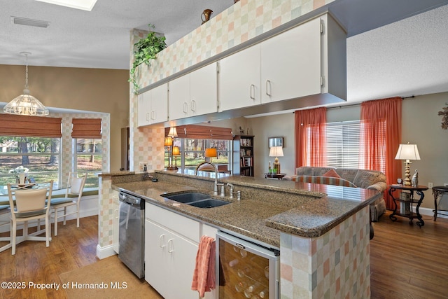 kitchen with dark stone countertops, white cabinets, a sink, and stainless steel dishwasher