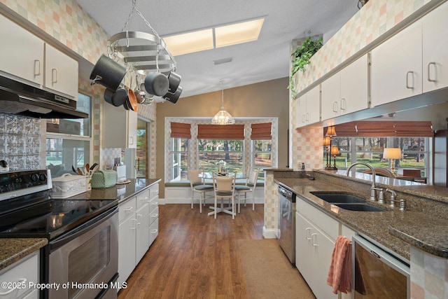 kitchen with under cabinet range hood, a sink, white cabinetry, appliances with stainless steel finishes, and pendant lighting