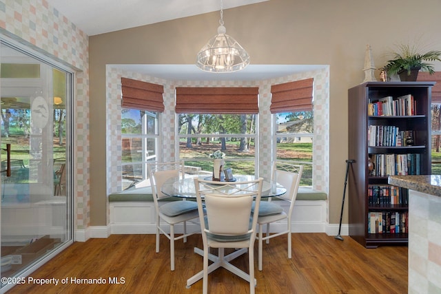 dining area featuring a chandelier, baseboards, wood finished floors, and lofted ceiling