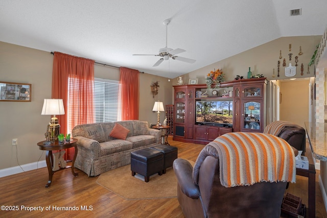 living room with lofted ceiling, ceiling fan, wood finished floors, visible vents, and baseboards