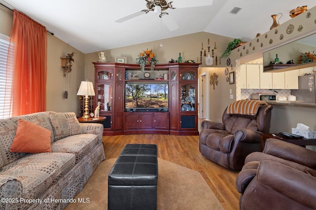 living area featuring light wood-style floors, visible vents, vaulted ceiling, and a ceiling fan