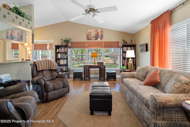 living room featuring a ceiling fan, vaulted ceiling, light wood-style flooring, and baseboards