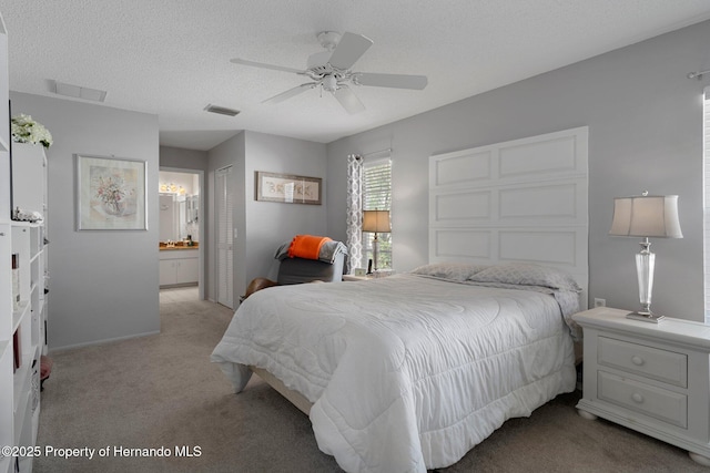 bedroom featuring a textured ceiling, ensuite bathroom, light carpet, visible vents, and a closet