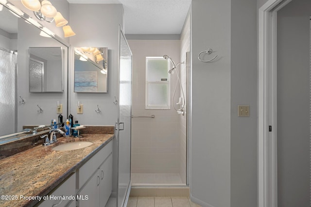 bathroom featuring tile patterned floors, vanity, a shower stall, and a textured ceiling