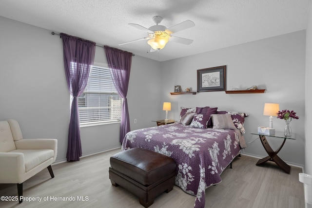 bedroom featuring a ceiling fan, light wood-type flooring, a textured ceiling, and baseboards