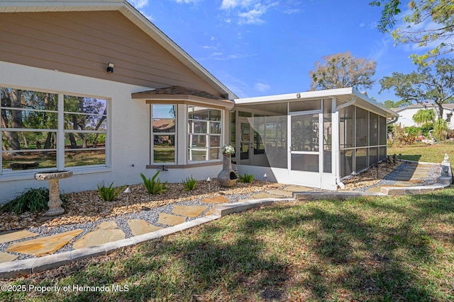 rear view of house featuring a sunroom and a yard