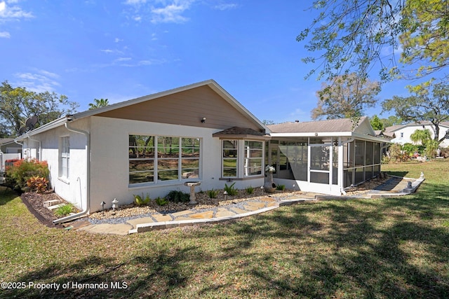 back of property featuring a lawn, a sunroom, and stucco siding