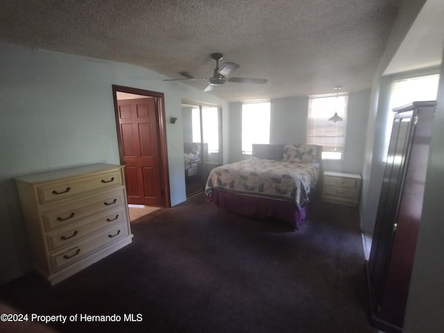 bedroom featuring ceiling fan, a textured ceiling, and dark colored carpet