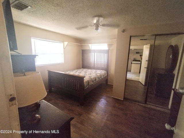 bedroom with ceiling fan, dark wood-type flooring, and a textured ceiling