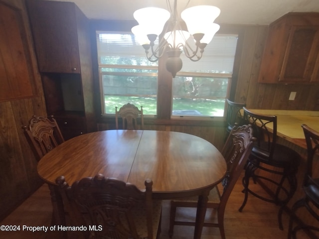 dining room featuring an inviting chandelier and wood walls