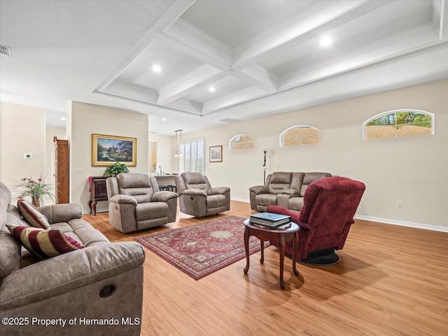 living room with coffered ceiling, light hardwood / wood-style flooring, beamed ceiling, and a healthy amount of sunlight