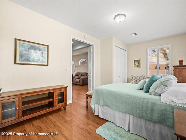 bedroom with a textured ceiling, light hardwood / wood-style floors, and a closet