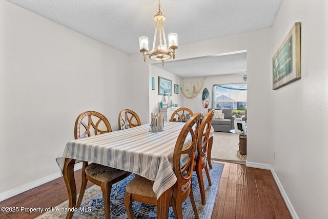 dining space featuring a textured ceiling, hardwood / wood-style flooring, and a chandelier