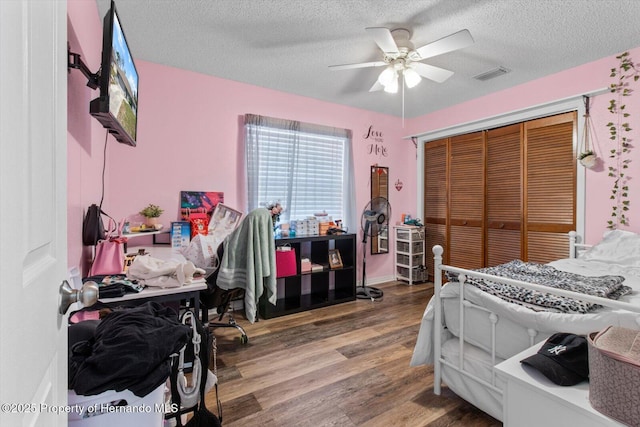 bedroom featuring a textured ceiling, a closet, hardwood / wood-style floors, and ceiling fan