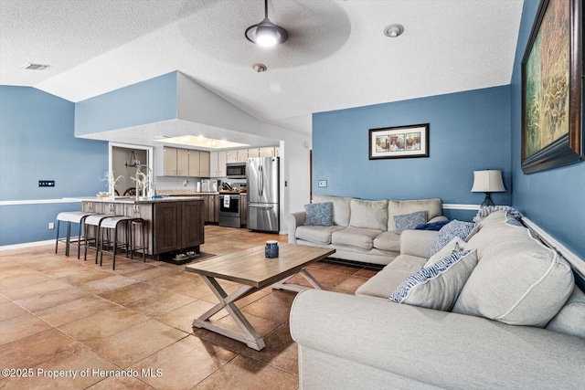 tiled living room featuring a textured ceiling, vaulted ceiling, and ceiling fan