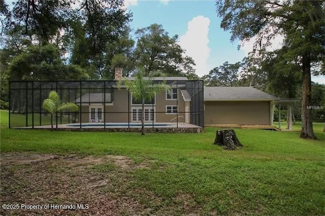 back of house with a fenced in pool, glass enclosure, and a lawn