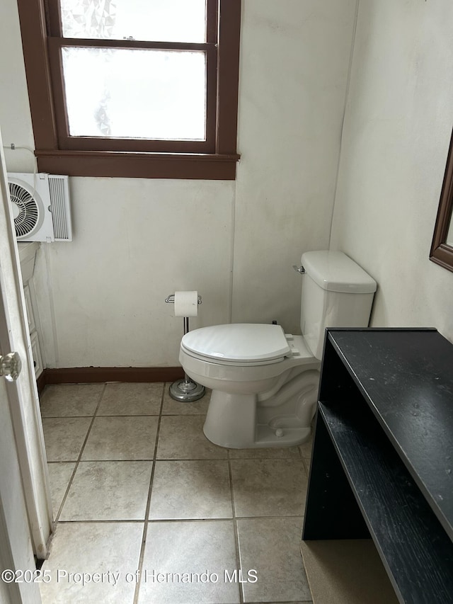 bathroom featuring tile patterned flooring, cooling unit, and toilet