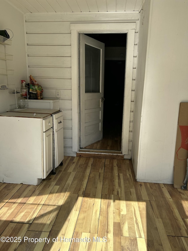 interior space with light hardwood / wood-style flooring and wooden walls