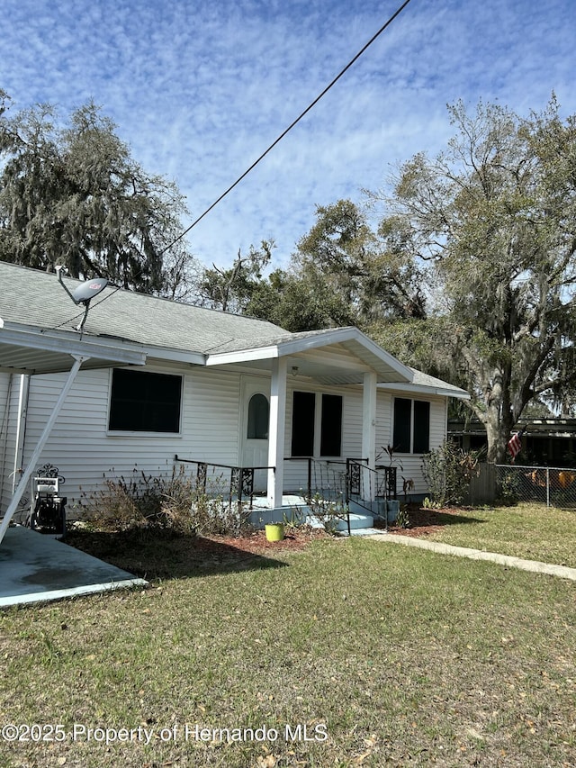 rear view of house featuring a lawn and a porch