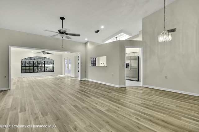 unfurnished living room with high vaulted ceiling, baseboards, visible vents, and light wood finished floors