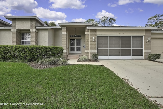 prairie-style house with brick siding, an attached garage, concrete driveway, and a front yard