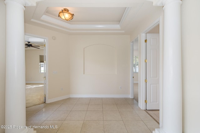 tiled empty room with crown molding, a tray ceiling, ceiling fan, and ornate columns