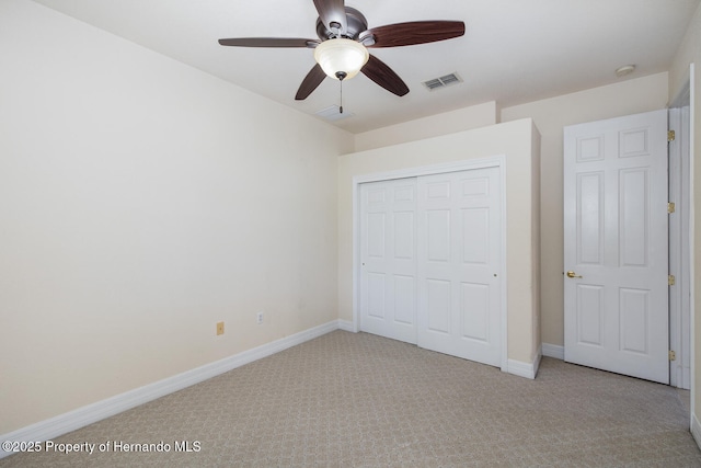 unfurnished bedroom with light colored carpet, ceiling fan, and a closet