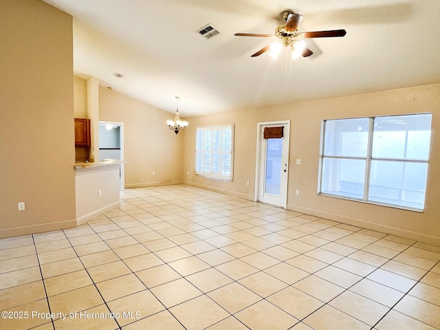 empty room with light tile patterned floors, lofted ceiling, visible vents, baseboards, and ceiling fan with notable chandelier