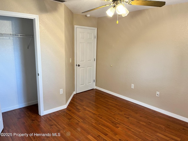 unfurnished bedroom with baseboards, visible vents, ceiling fan, wood finished floors, and a closet