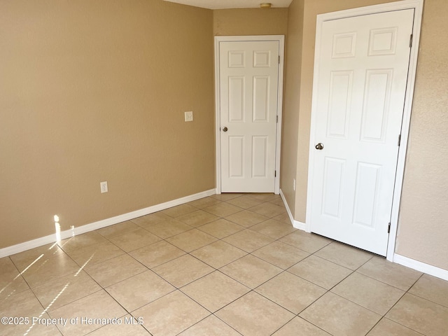 empty room featuring baseboards and light tile patterned floors