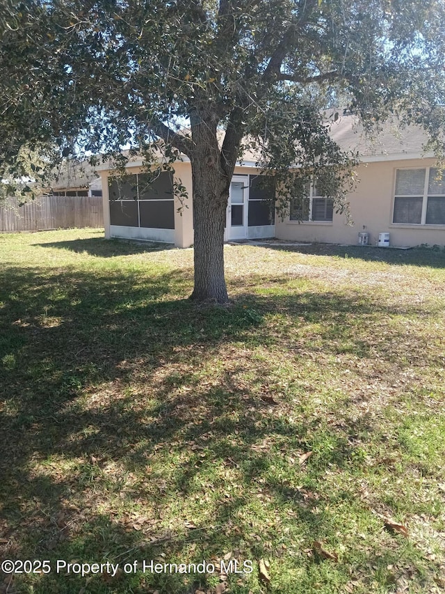 view of yard featuring a sunroom and fence