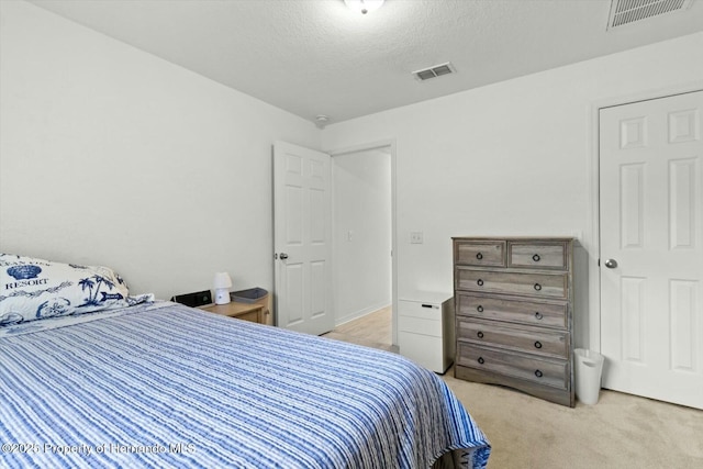 bedroom featuring a textured ceiling and light colored carpet