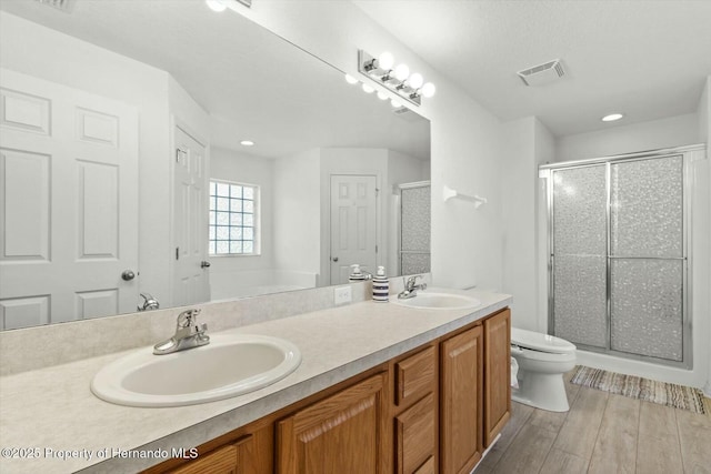 bathroom featuring toilet, vanity, an enclosed shower, and wood-type flooring