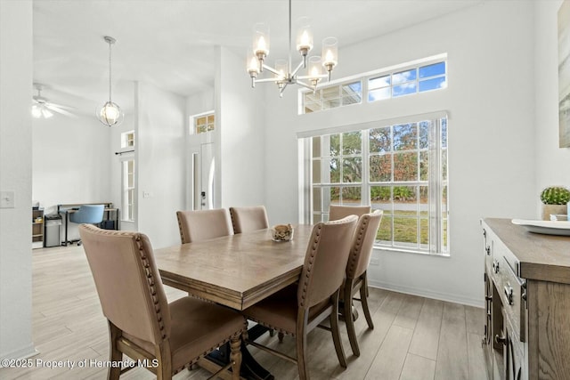 dining area with a notable chandelier, light hardwood / wood-style floors, and a high ceiling