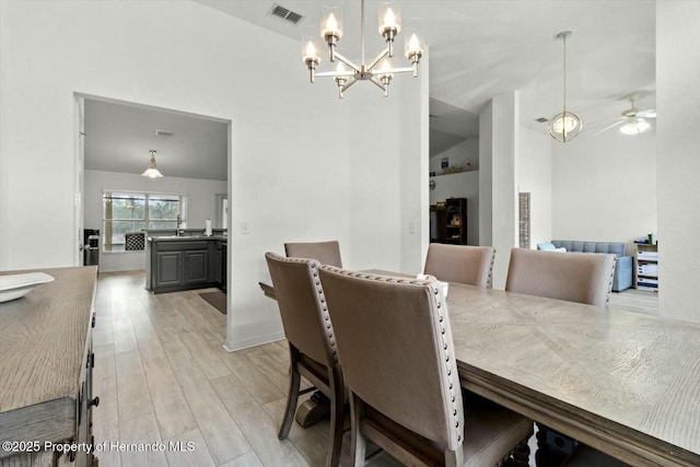 dining room featuring light wood-type flooring and ceiling fan with notable chandelier